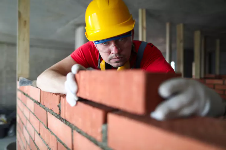 Insured bricklayer laying a brick