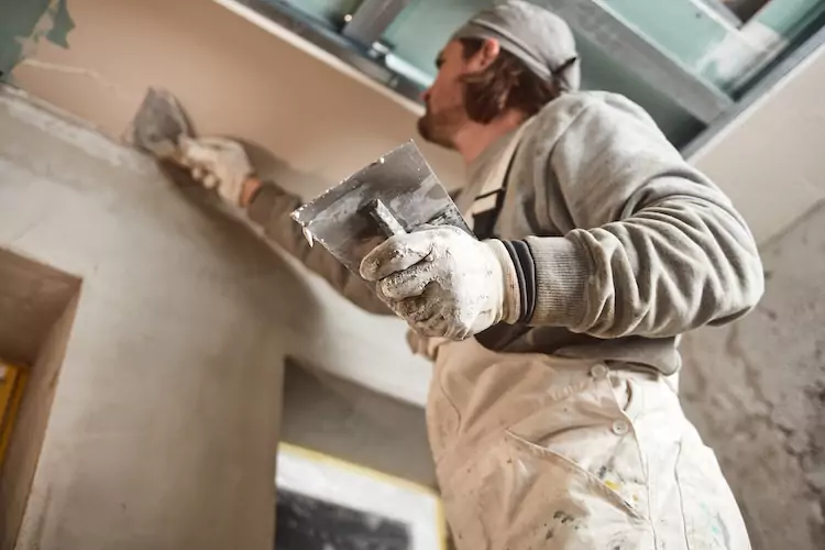 Plasterer with public liability coverage applying gypsum