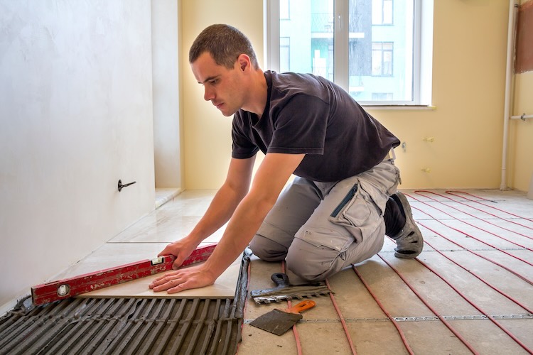 Tiler with tilers insurance applying tile to plaster