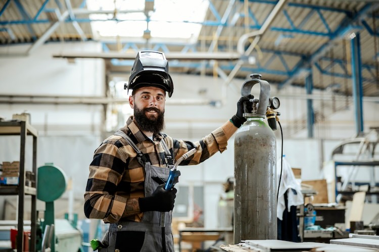 Welder with welders insurance smiling in a warehouse