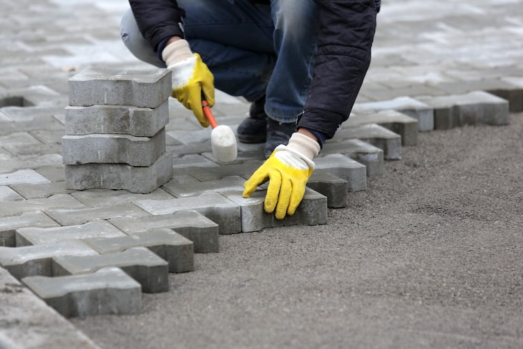 Paving stone worker is putting down pavers during a construction of a city street