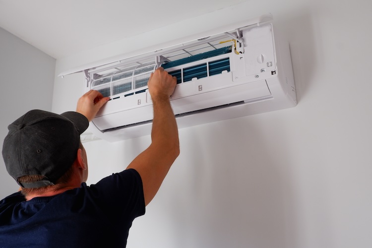 AC mechanic with air conditioning insurance repairing an aircon