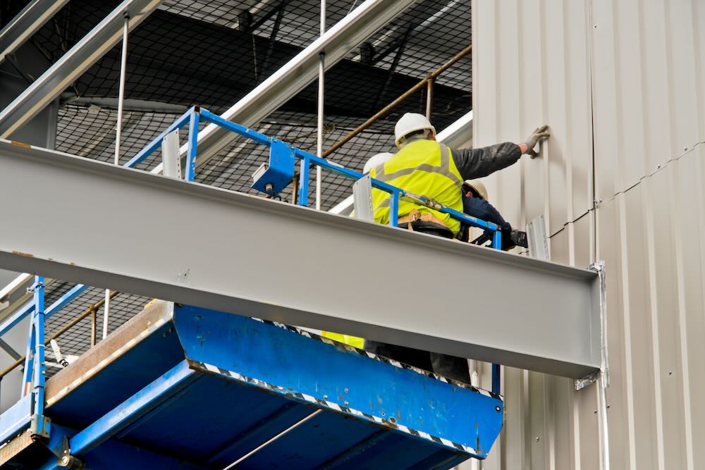 Insured cladding installer installing cladding to a building under construction,