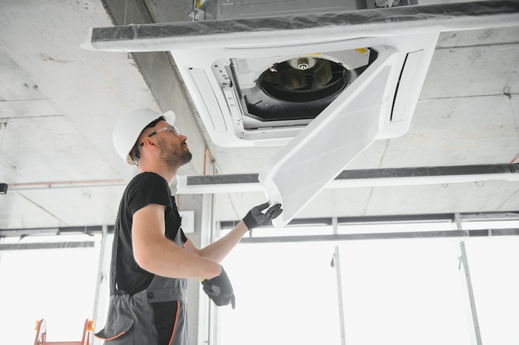 Air con installer cleans air conditioner system in a modern apartment.