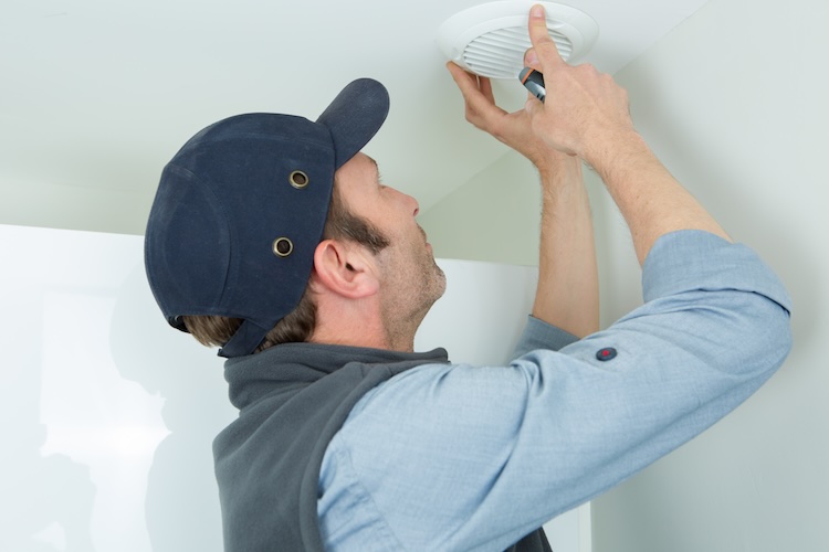 Alarm installer installing a smoke alarm