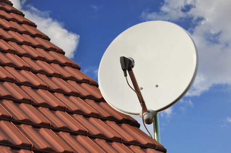 White dish antenna on a roof with red tiles