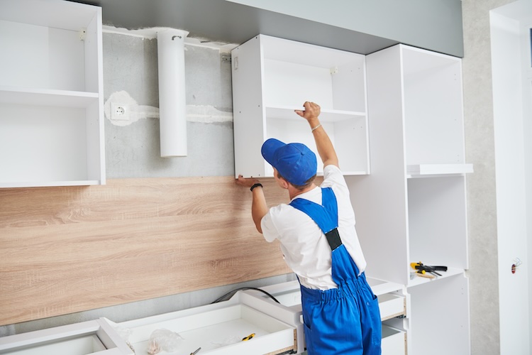 Kitchen fitter installing a cabinet